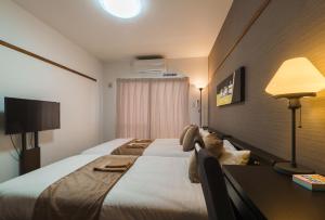 那覇市にあるKINTARO Hotel Okinawa Nahaの大きなベッドとデスクが備わるホテルルームです。