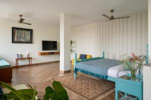 a bedroom with a blue bed and a tv at Three Kings in Panaji