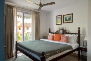 a bedroom with a bed with orange pillows and a window at Three Kings in Panaji