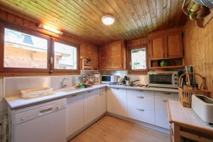 a kitchen with white cabinets and a wooden ceiling at Chalet L’eau vive - Happy Rentals in Chamonix-Mont-Blanc