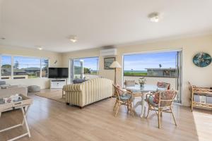 a living room with a couch and a table and chairs at Otaki Beach Haven - Otaki Beach Holiday Unit in Otaki