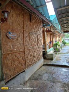 a building with a wooden wall with a sign on it at Ameen Homestay อามีน โฮมสเตย์ in Ban Komo Sam Sip Paet