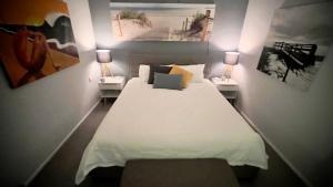 a bedroom with a large white bed with two lamps at The Ocean Street House in Budgewoi