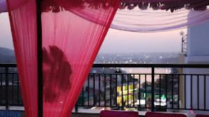 a red curtain on a balcony with a view at BLISS GANGA RISHIKESH , Uttarakhand in Rishīkesh