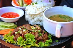 un piatto di cibo con una tazza di zuppa e riso di The Peace House - Siem Reap a Phumĭ Sândăn