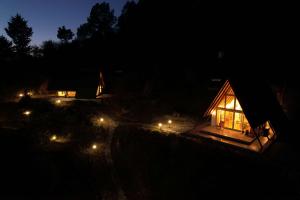 uma pequena cabana iluminada à noite com luzes em amã Stays & Trails Godhuli Cottages Naukuchiatal em Nainital
