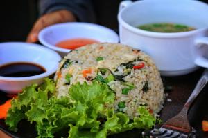 a plate of rice and lettuce and a bowl of soup at The Peace House - Siem Reap in Phumĭ Sândăn
