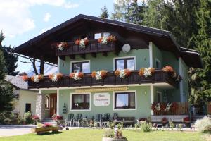 un bâtiment vert avec des boîtes de fleurs sur le balcon dans l'établissement Haus Petersmann, à Ramsau am Dachstein