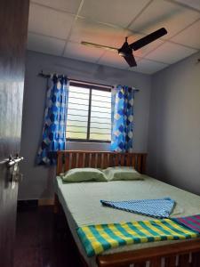 1 dormitorio con 1 cama, ventilador de techo y ventana en KENSONS BUDGETSTAY NON AC FREE WIFI and PARKING, en Mangalore