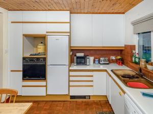 a kitchen with white cabinets and a black refrigerator at Smiddy Cottage in Alyth