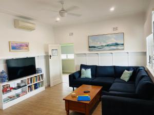 a living room with a blue couch and a tv at Christina Cottage in South West Rocks