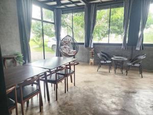 uma sala de jantar com mesas, cadeiras e janelas em November Garden ชัยนาท 
