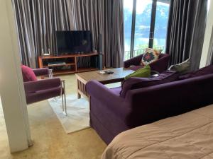 - un salon avec deux canapés violets et une télévision dans l'établissement Morocco Blue cafe by Chilong River Farm Resort, à Muang Kosum