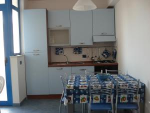 a kitchen with a table with chairs and white cabinets at Casa Vacanze Kamarina in Punta Secca