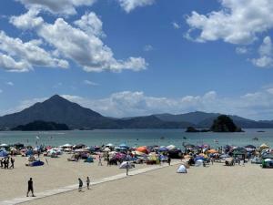 grupa ludzi na plaży z parasolami w obiekcie Sea View Inn MURAMIYA w mieście Wada