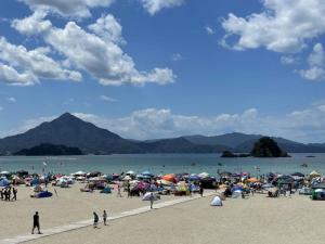 a group of people on a beach with umbrellas at Sea View Inn MURAMIYA in Wada