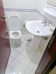 MBZ - Pleasant Stay في أبوظبي: حمام ابيض مع مرحاض ومغسلة