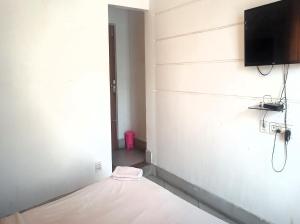 Zimmer mit einem Bett und einem TV an der Wand in der Unterkunft Mountain Green Club and Resort in Shiliguri
