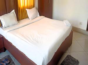 a large bed with white sheets and pillows on it at Mountain Green Club and Resort in Siliguri