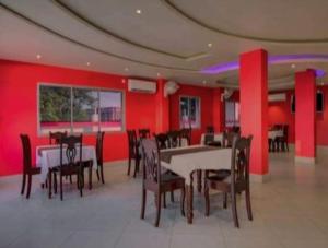 ein Esszimmer mit roten Wänden, Tischen und Stühlen in der Unterkunft Mountain Green Club and Resort in Shiliguri