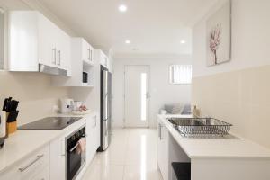 a white kitchen with white cabinets and a sink at New Listing, Wi-Fi and Laundry in Brisbane