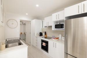 a kitchen with white cabinets and a stainless steel refrigerator at New Listing, Wi-Fi and Laundry in Brisbane