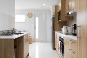 uma cozinha com pisos brancos e armários de madeira em Super Host, Well Presented with Wi-Fi! em Brisbane
