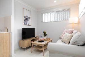 a white living room with a white couch and a tv at Super Host, Well Presented with Wi-Fi! in Brisbane