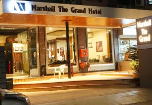 a store front of a grand hotel with a chair inside at Marshall The Grand Hotel in Ahmedabad