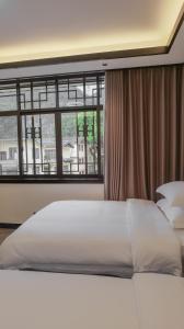 a bedroom with a white bed and a window at Guilin Meishe Homestay in Guilin