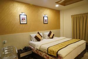 um quarto de hotel com uma cama e duas fotografias na parede em Marshall The Grand Hotel em Ahmedabad