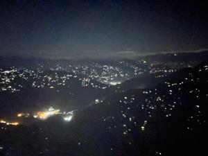 uma vista de uma cidade iluminada à noite em Delohighs em Kalimpong