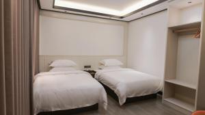 two beds in a room with white sheets at Guilin Meishe Homestay in Guilin