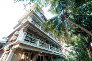 a building with a balcony and a palm tree at Itsy By Treebo - Adams Beach Resort 350 Mtrs From Baga Beach in Baga