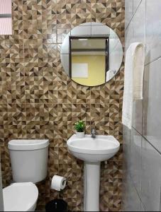 a bathroom with a toilet and a sink and a mirror at Pousada Coqueiros in Cabo Frio