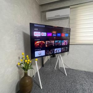 einen großen Flachbild-TV an der Wand mit einer Blumenvase in der Unterkunft Apartment in Gangnam in Seoul