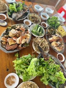 a wooden table with plates of food on it at Đảo Chè Thanh Chương - Điếu Cày Travel in Trai Ðỏ