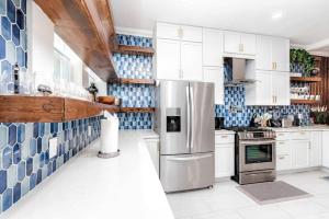 a kitchen with white cabinets and blue tiles on the wall at Home 4/ King Beds - Large Garage by StayStLouis in Soulard