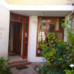 an entrance to a house with a window and a bush at La Chinita hospedaje Cajamarca in Cajamarca