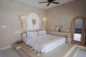 a bedroom with a large white bed and a mirror at Gili Boho Villas - Aesthetic Private Pool Villas in Gili Trawangan