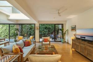 ein Wohnzimmer mit einem Sofa und einem TV in der Unterkunft Aalia Villas Anjuna, Goa by Aalia Collection in Anjuna