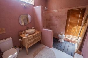 ein Badezimmer mit einem Waschbecken, einem WC und einem Spiegel in der Unterkunft Gili Boho Villas - Aesthetic Private Pool Villas in Gili Trawangan
