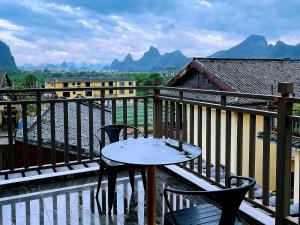 einen Tisch und Stühle auf einem Balkon mit Bergblick in der Unterkunft Guilin Meishe Homestay in Guilin