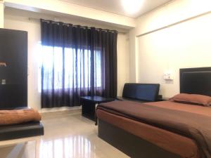 1 dormitorio con 1 cama y una ventana con cortinas en THE Pi HOTEL IMPHAL MANIPUR, en Imphal