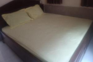 Una cama con sábanas blancas y almohadas. en OYO 93582 Liani Homestay Syariah, en Kuripan