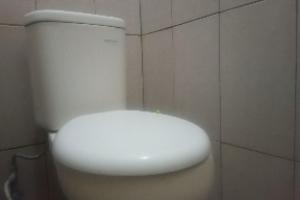 a white toilet in a bathroom with a tiled wall at OYO 93582 Liani Homestay Syariah in Kuripan