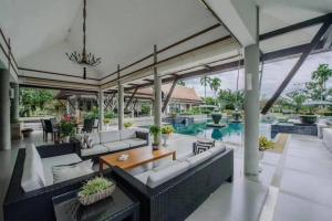 an outdoor living room with couches and a pool at Oasis Villa Pattaya in Ban Bung
