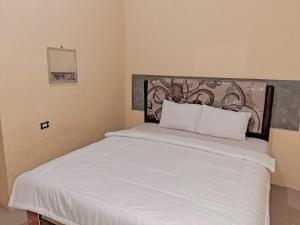 - une chambre avec un grand lit et des draps blancs dans l'établissement OYO 93590 Penginapan Palapa 10 Syariah, à Bandar Lampung