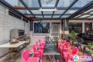 a patio with pink chairs and tables and a grill at Baby Dolphin in Hengchun