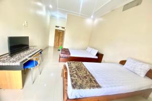 Schlafzimmer mit einem Bett, einem Schreibtisch und einem TV in der Unterkunft OYO 93600 Barong Ijo Homestay Syariah in Yogyakarta